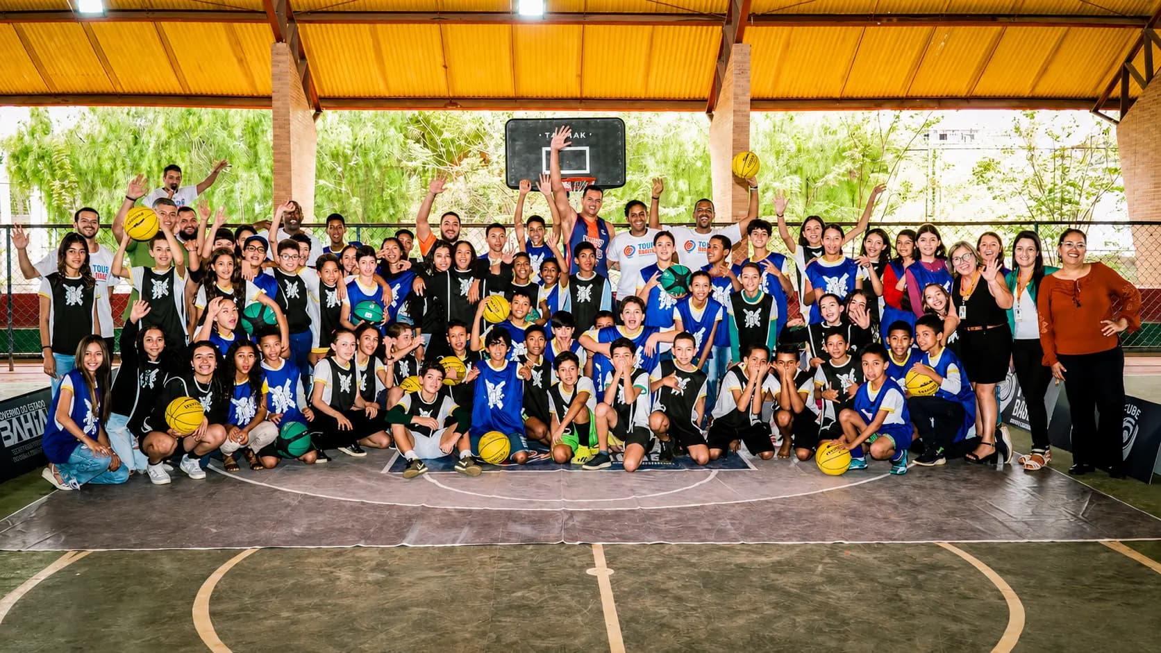 Crianças, educadores e equipe reunidos em uma quadra esportiva