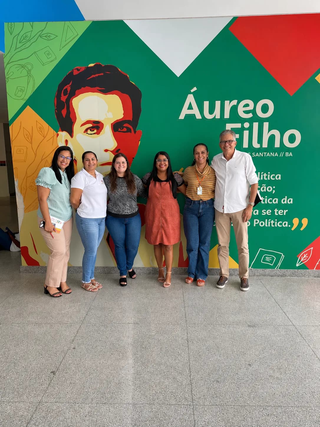 Grupo diante de mural escolar colorido durante agenda de mobilização educacional