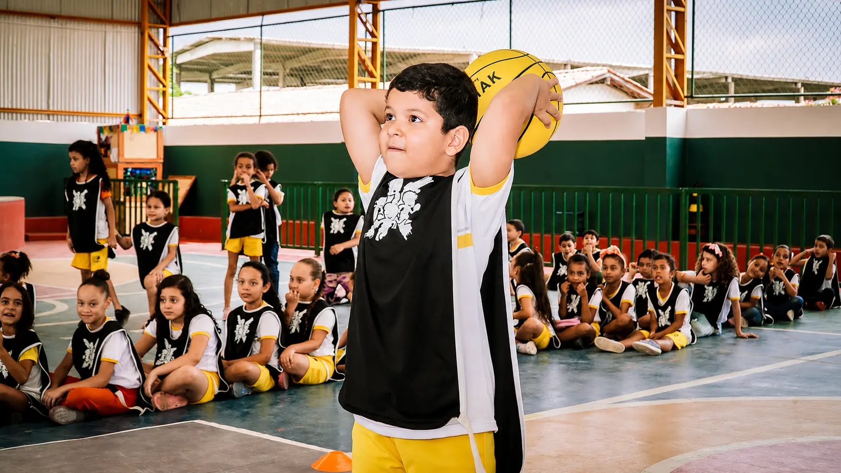 Estudante pratica movimento com bola durante clínica esportiva